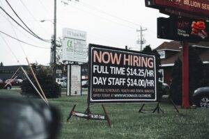 Outdoor hiring sign advertising restaurant job openings with competitive wages and benefits.